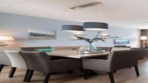 Un comedor moderno con una mesa de madera, sillas grises e iluminación colgante.