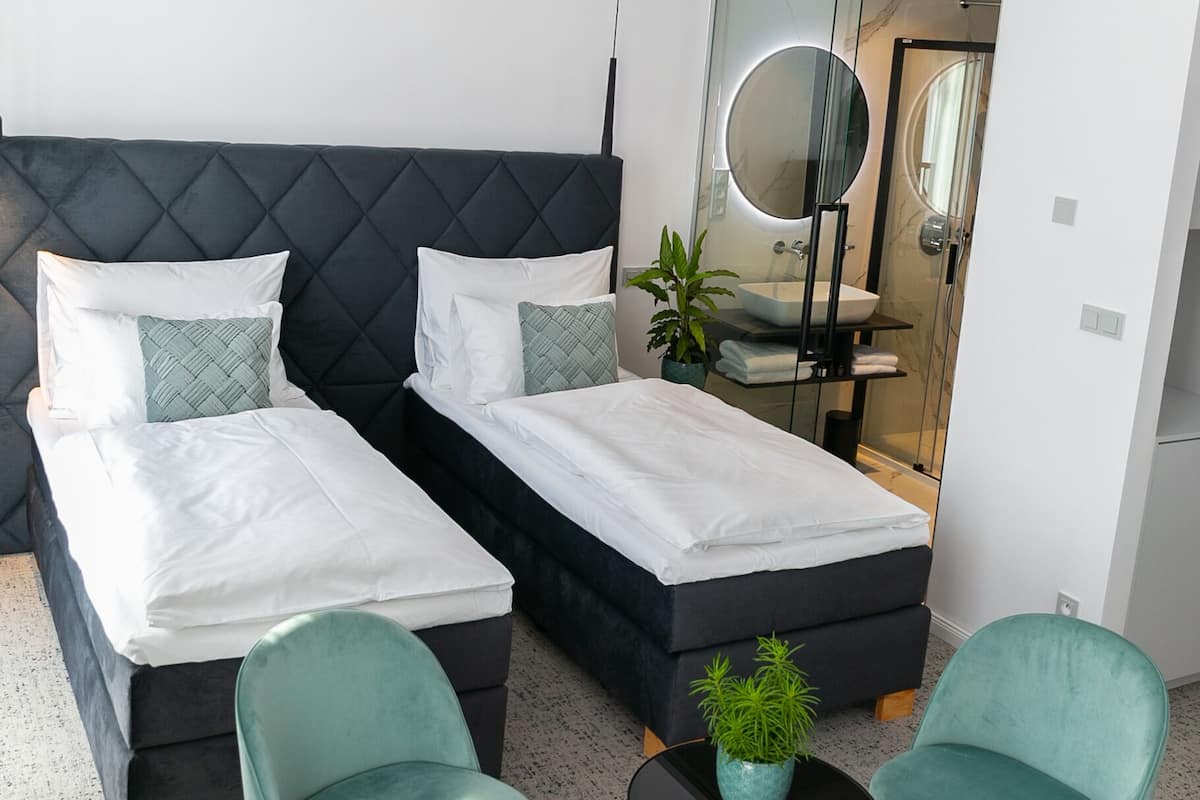 A modern bedroom with two beds, a round mirror, a round table, and two chairs.