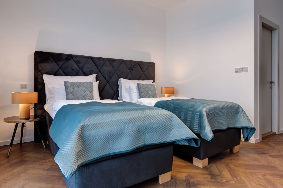 A double bed with a dark headboard, two bedside tables with lamps, and a wooden floor.