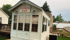 A white building with a sign reading "The Halfway B&B" and a number "1433 C" on the side. - Halfway Tiny House - 3 BR Small Town Iowa Rural Setting! (Britt)