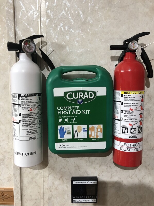 Three fire extinguishers, a first aid kit, and a thermostat control panel.