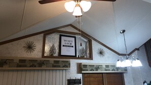 A ceiling fan with a light fixture, a framed sign stating "WiFi is on the house," and decorative wall elements. - Halfway Tiny House - 3 BR Small Town Iowa Rural Setting! (Britt)