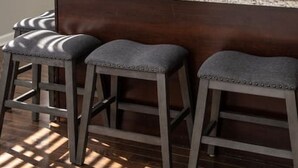 A modern kitchen with dark wood cabinets, stainless steel appliances, and a granite countertop. There are three bar stools and a small island with a plant. - Stylish 2BR near it all (Cincinnati)