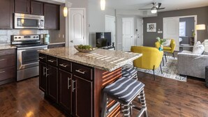 A modern kitchen with dark cabinetry, stainless steel appliances, and a granite countertop. - Stylish 2BR near it all (Cincinnati)