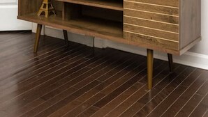 Een houten entertainmentsmeubel met een flatscreen televisie, verschillende planken en een lade.