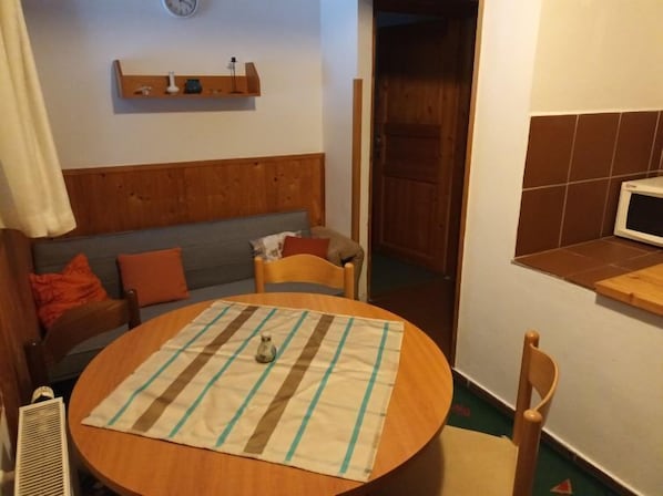 A cozy room with a wooden headboard, a round table with a striped tablecloth, a small vase, and a wooden chair. - Compact Mountain Base by Interhome (Harrachov)