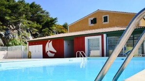 Ein Schwimmbad mit Rettungsschwimmturm und einem Gebäude mit roter und gelber Fassade.