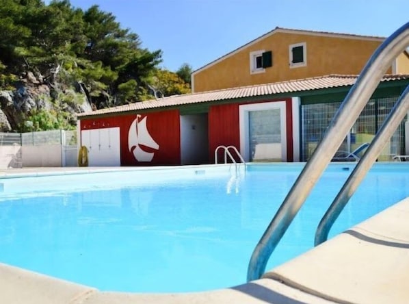 A swimming pool with a lifeguard tower and a building with a red and yellow facade.