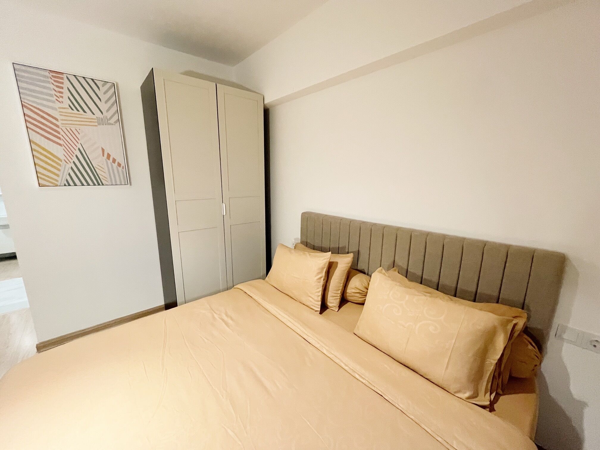 Un dormitorio con cama, armario y una obra de arte en la pared.