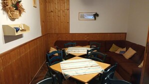 Un espace repas avec des murs en bois, un canapé marron et des tables recouvertes de nappes à rayures.