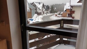 Uitzicht vanuit een raam op een woonwijk met huizen en een met sneeuw bedekte weg.