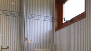 Een badkamer met douche, toilet en wastafel.