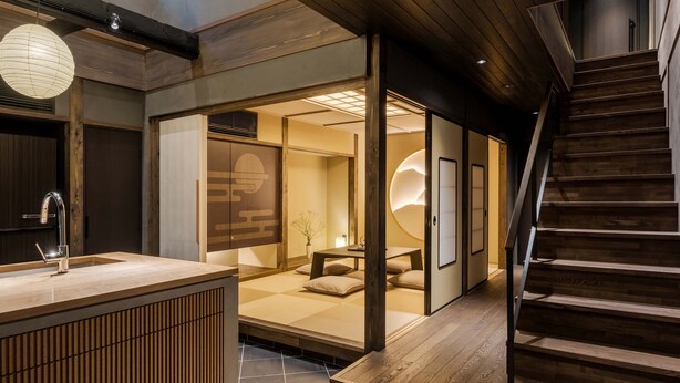 Un interno moderno con una scala in legno, una porta scorrevole con cornice in legno e un pavimento piastrellato.
