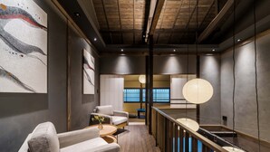 Un interno moderno con soffitto in legno, un divano, un tavolino con un vaso e vista su una piscina.