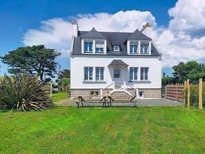A two-story house with a stone foundation, a front porch, and a well-maintained lawn. - An Neizh by Interhome (Locquirec)