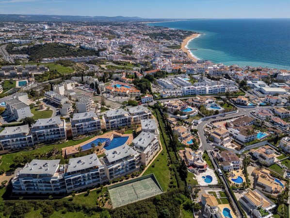 Vue aérienne d’une zone balnéaire comprenant plusieurs bâtiments d’hôtel, des piscines et une plage.