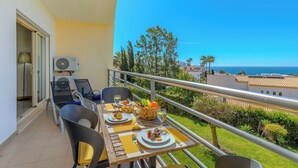 A balcony with a table set for two, outdoor furniture, and a view of the sea. - Vista Mar by Interhome (Albufeira)