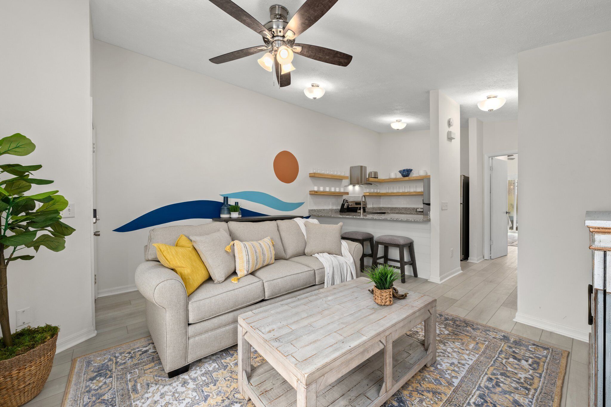 A modern living room with a grey sofa, a wooden coffee table, and a ceiling fan.