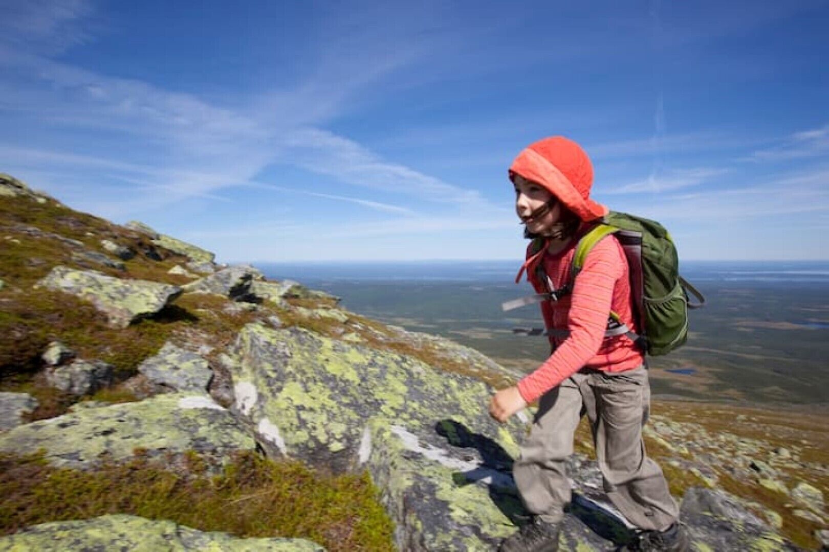 Un excursionista en un sendero rocoso de montaña con una vista despejada del paisaje.