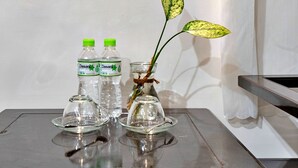 Un tavolo con due bottiglie d'acqua Dasani, un vaso di vetro con una pianta e un bicchiere.