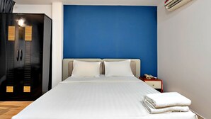 Una camera d'albergo con un letto, un comodino, un armadio e una parete azzurra.