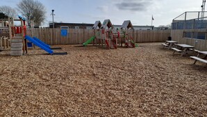 Een speeltuin met een glijbaan, klimconstructies en picknicktafels.