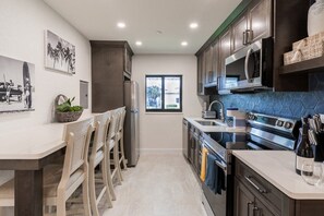 A modern kitchen with a central island, stainless steel appliances, and a view to the outside.
