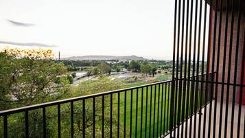 Een balkon met uitzicht op een groen veld en gebouwen in de verte.