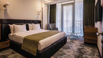 Una habitación de hotel con una cama grande, una silla, una mesita y un televisor.