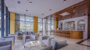Un área de descanso moderna con sofás, un bar y vistas al exterior.