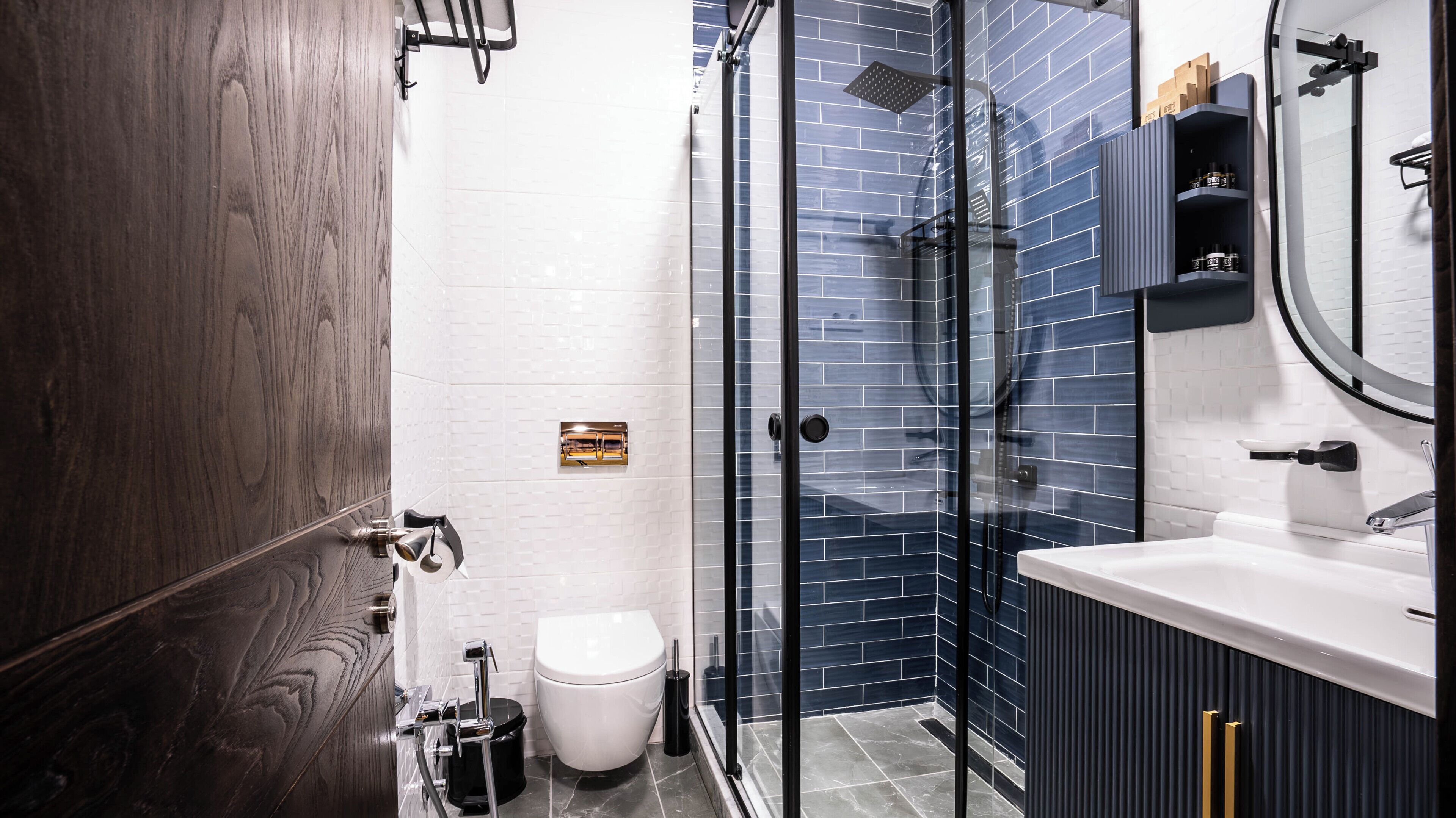 A modern bathroom with a glass-enclosed shower, a white toilet, and a vanity with a mirror.