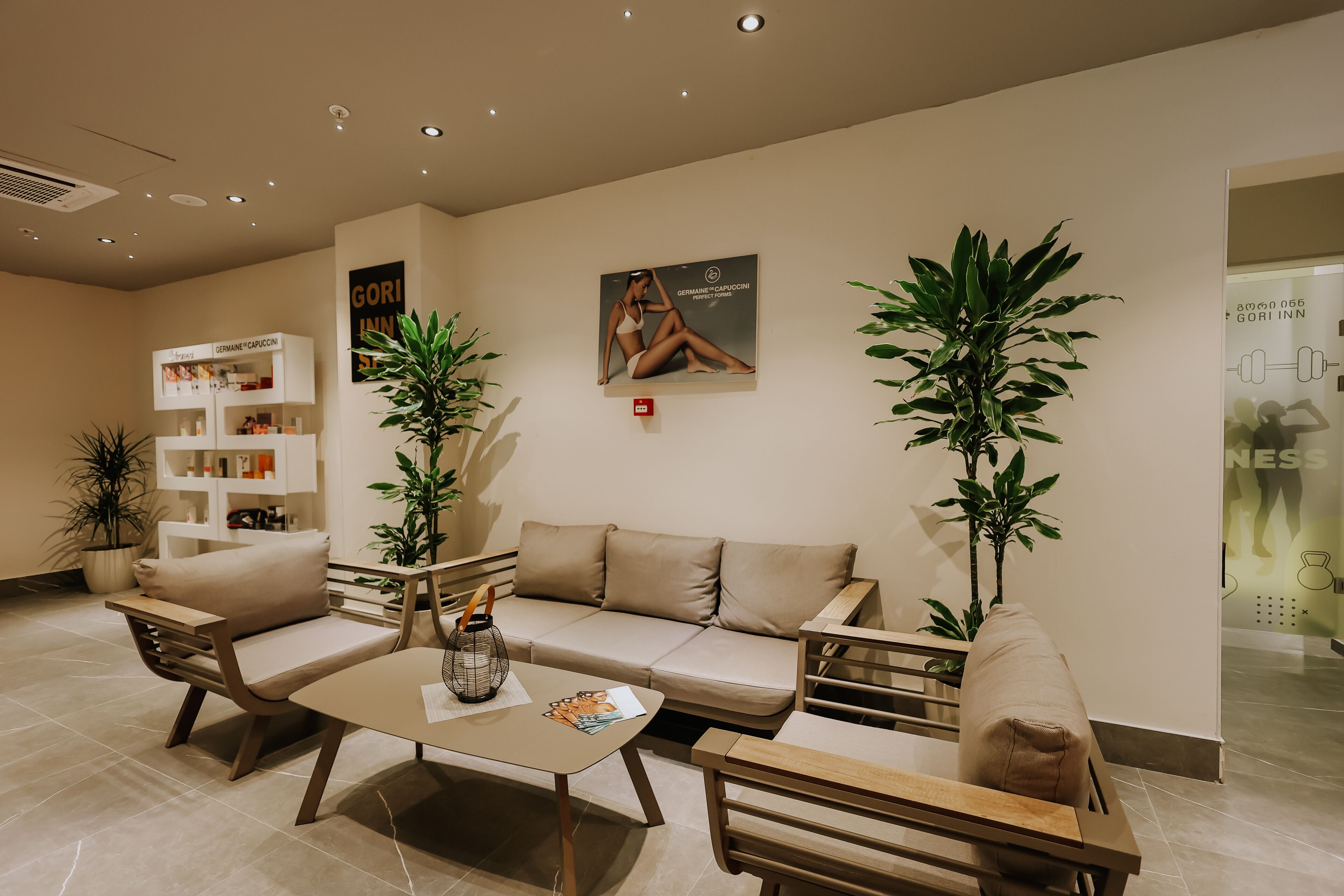 A modern reception area with a sofa, chairs, a coffee table, and a bookshelf.