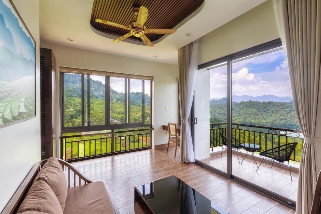 Uma sala de estar espaçosa com uma grande porta de vidro que se abre para uma varanda com vista para as montanhas.