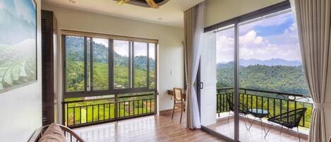 A spacious living room with a large sliding glass door leading to a balcony with a mountain view.