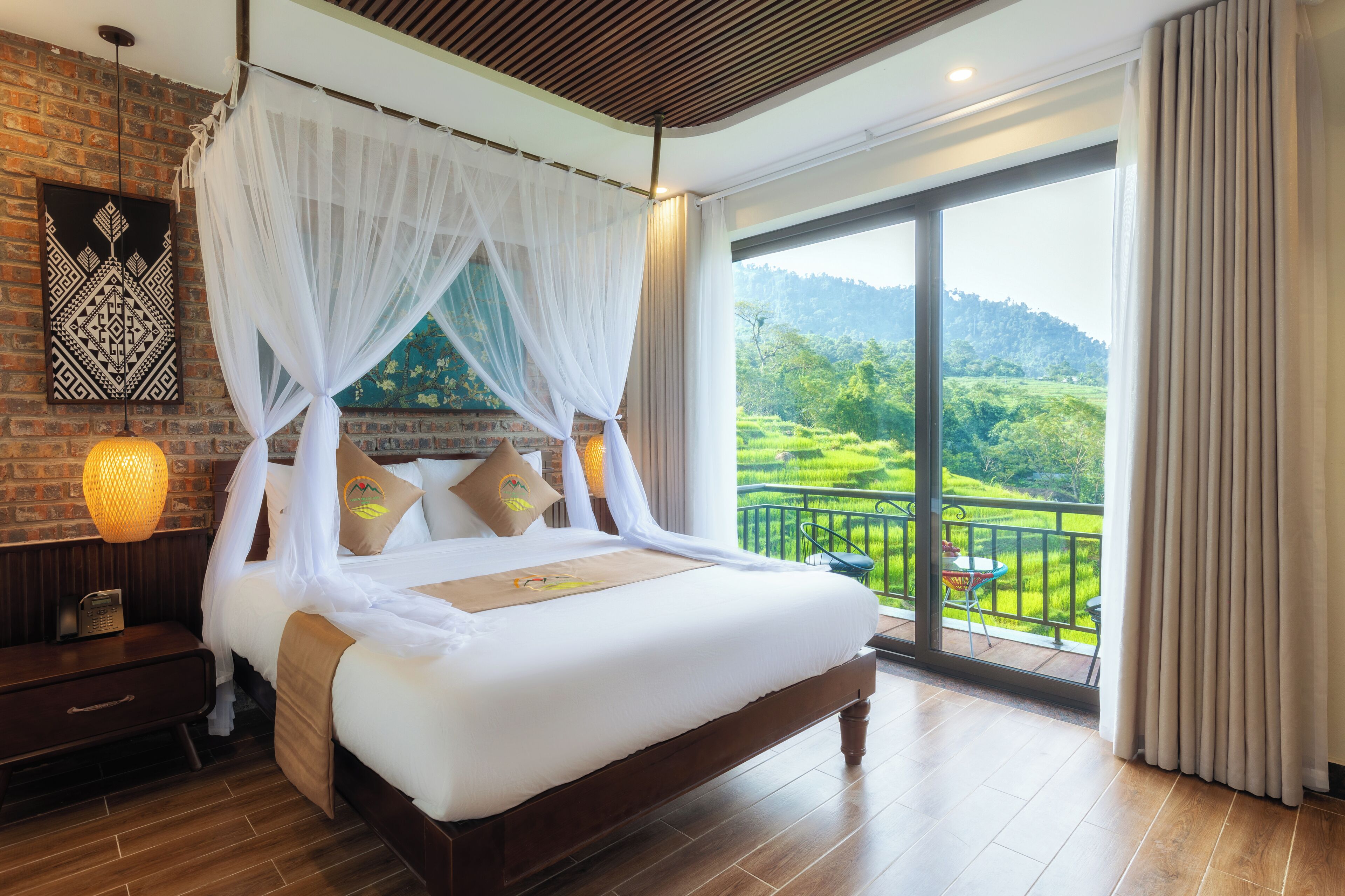 A spacious bedroom with a large bed, a wooden headboard, a nightstand, a bedside table, and a view of lush greenery through a large window.