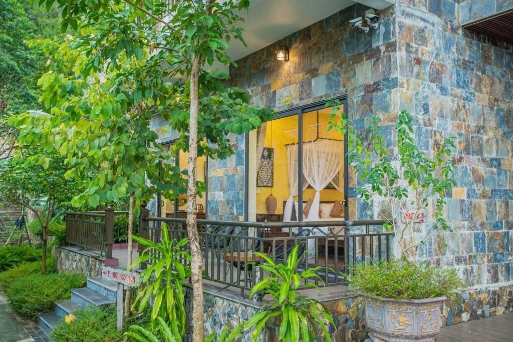 Um edifício com fachada de pedra, uma varanda com grade e plantas em vasos.