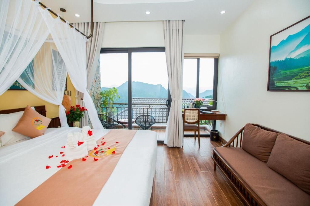 A hotel room with a bed, a balcony, a sofa, and a dining area.