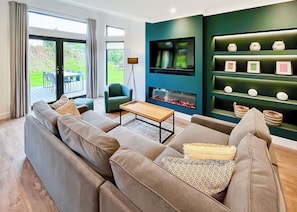 Ein modernes Wohnzimmer mit einer Couch, einem Couchtisch, einem Fernseher und einem Kamin.