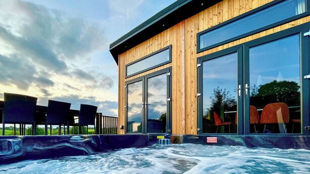 Ein Whirlpoolbereich mit Holzwänden und großen Fenstern, umgeben von Sesseln.