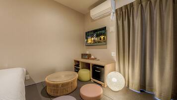 A hotel room with a bed, a small seating area with a round table and chairs, a television, and a window with curtains.