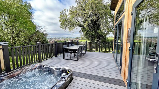 Una terraza con jacuzzi, asientos al aire libre y vistas al campo.