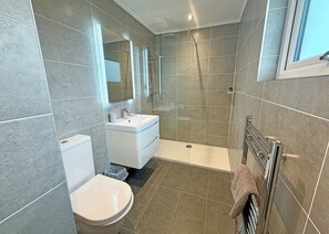 A modern bathroom with a toilet, sink, shower, and a towel rack.