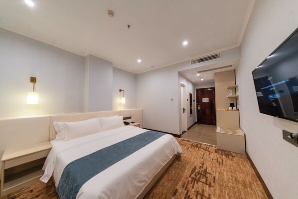 A hotel room with a large bed, bedside tables, a TV mounted on the wall, and a wooden floor. - Legend Hotel and Resort (Sihanoukville)