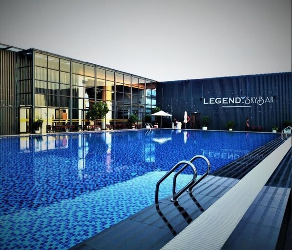 Ein Schwimmbad mit Glaswand und ein Gebäude mit der Beschilderung 'LEGENDSKY BAR'.