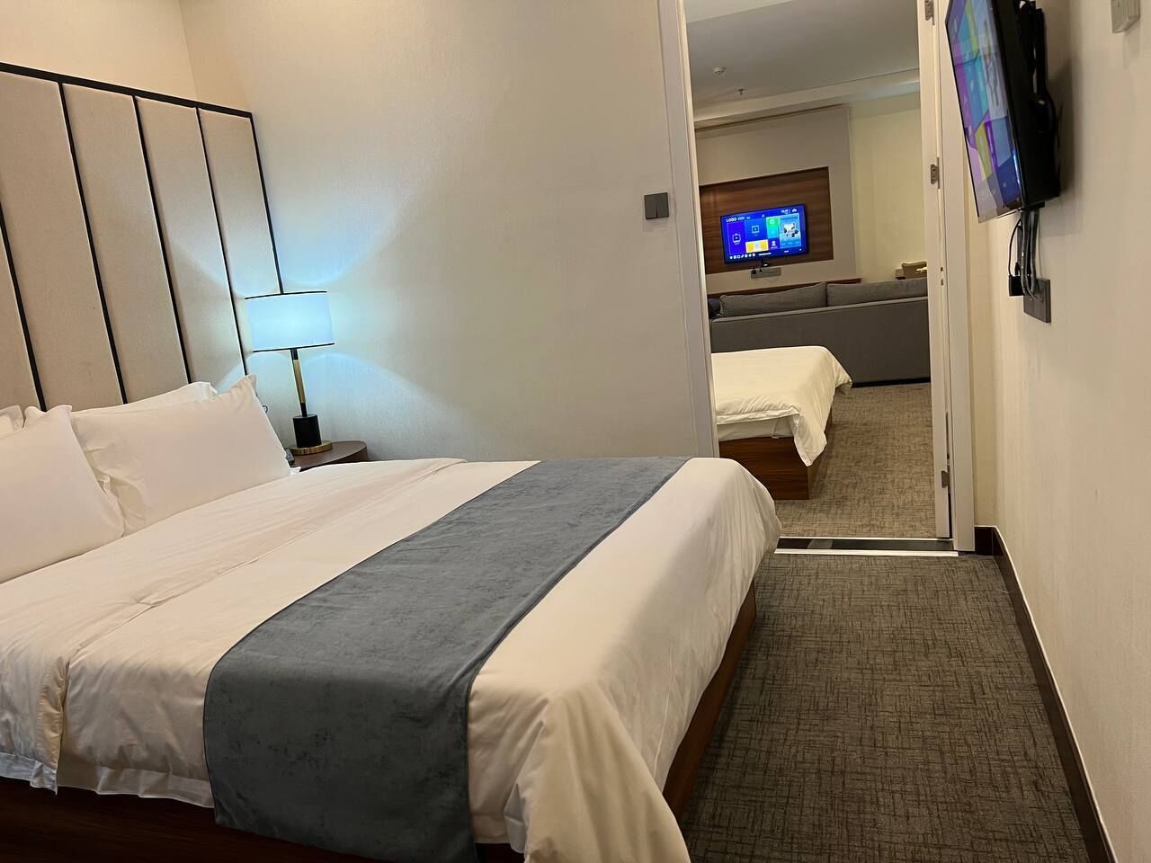 A hotel room with a bed, a TV, and a desk with a chair.