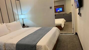 A hotel room with a bed, a TV, and a desk with a chair.
