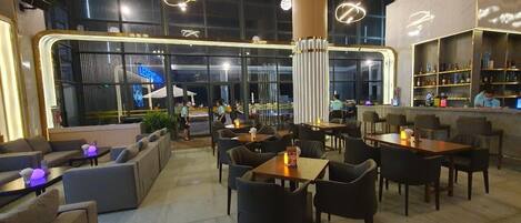 A modern restaurant with a bar area, seating arrangements, and large windows providing views.
