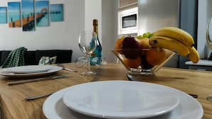 Un tavolo da pranzo con una ciotola di frutta, un bicchiere di vino e piatti.