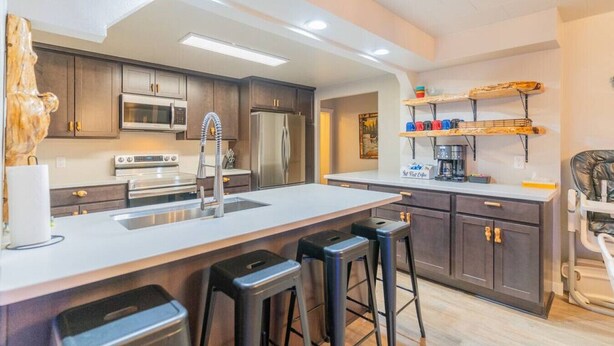 Una cocina moderna con armarios de madera oscura, electrodomésticos de acero inoxidable, una isla grande con taburetes y un área para café.