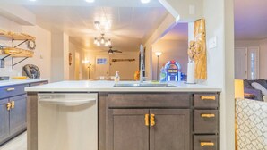 Una cocina moderna con una isla central, armarios oscuros y un ventilador de techo.